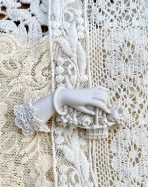 Resin Edwardian hand brooch holding a basket of flowers.