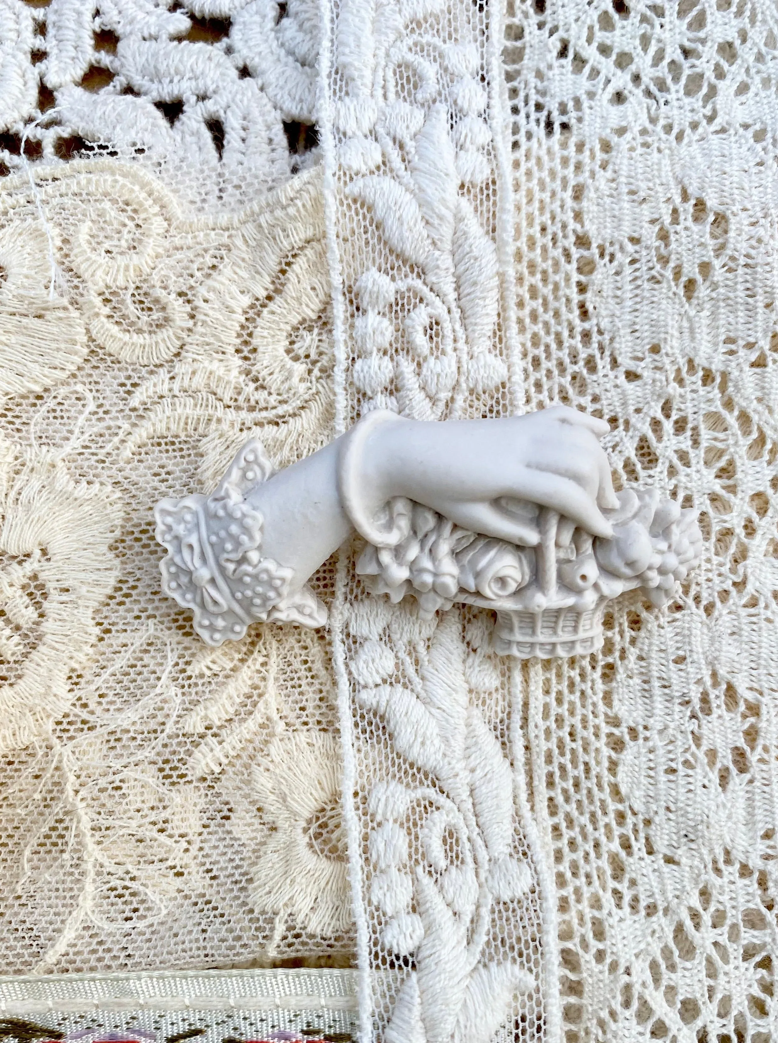 Resin Edwardian hand brooch holding a basket of flowers.