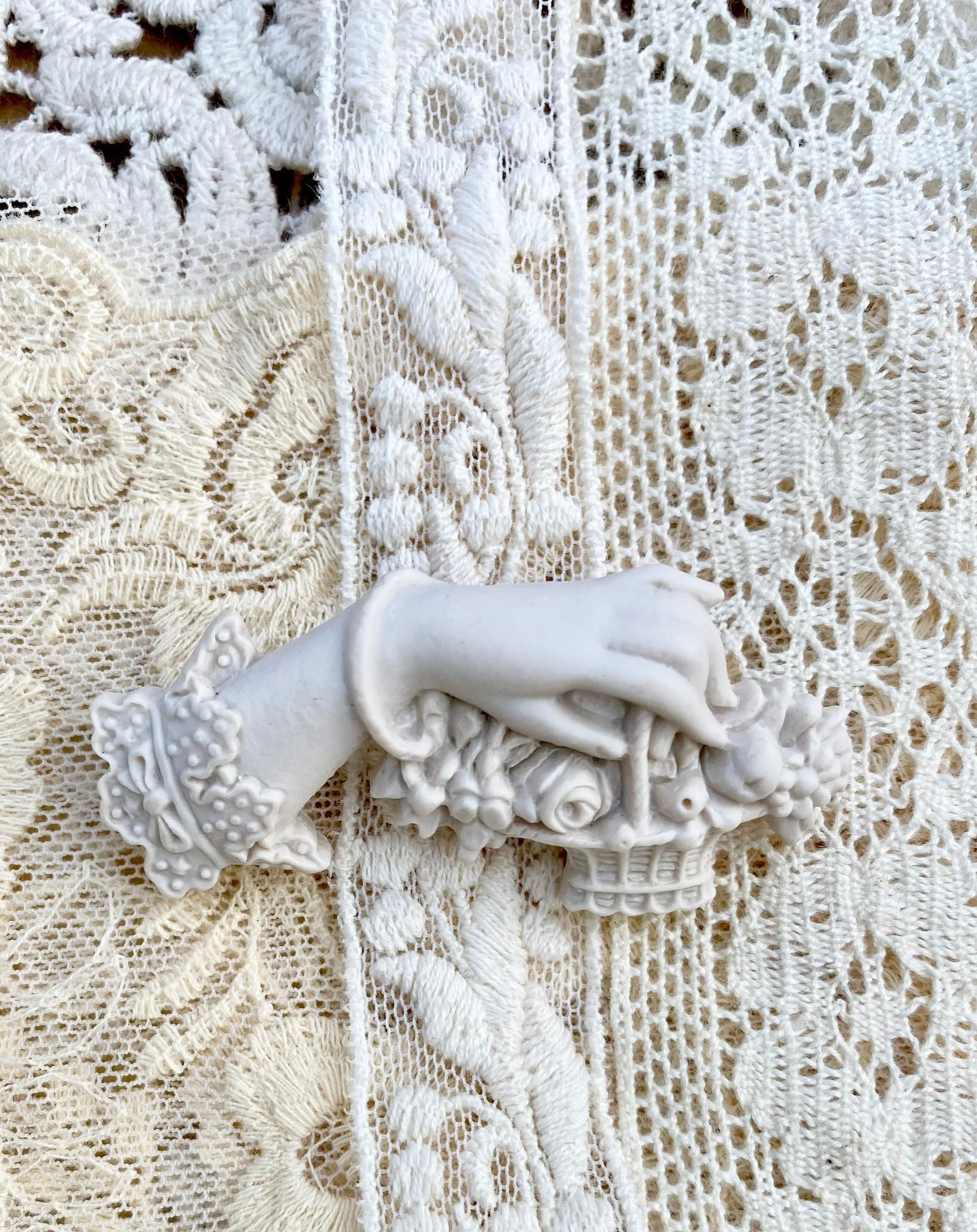 Resin Edwardian hand brooch holding a basket of flowers.